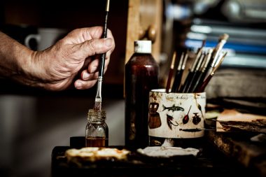 Photograph of a hand holding a varnish brush