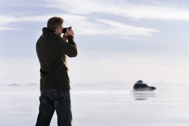 Lifestyle photograph of a man photographing a car in Bolivia