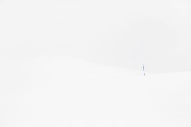 A single blue post in a snow covered landscape