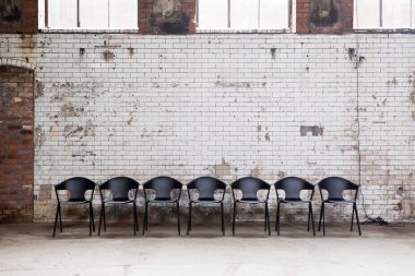 A row of contemporary black chairs in an abandoned power station