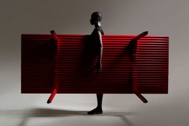 Photograph of a woman holding a red table in a photographic studion in London for Layer Design