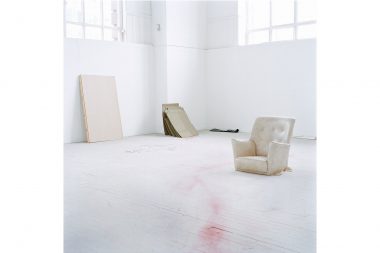 An armchair a various panels in a white art studio.
