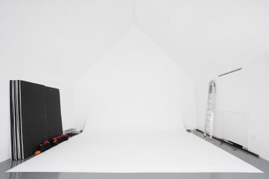 A white photographic studio with a ladder and reflector panels.