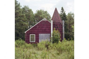 A small dark red church building by the road in Minnesota.