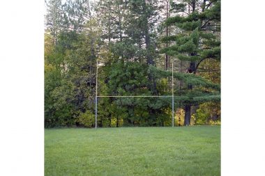 A yellow and blue goal post in front of trees in dilapidated Minnesota.