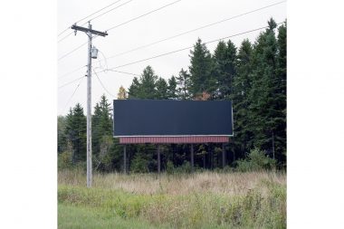 A black blank advertising hoarding by the side of the road.
