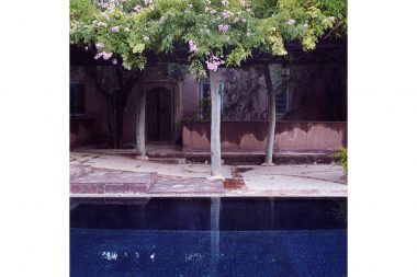 A blue pool by a building in Morocco with trees and flowers visible