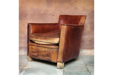 A brown leather chair on a stone floor with plaster walls