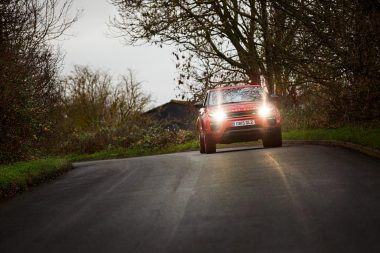 Range rover on a bend with headlights on by Richard Boll