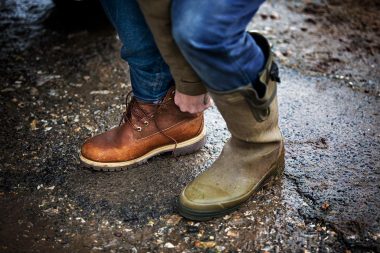 Man putting on walking boots by Richard Boll