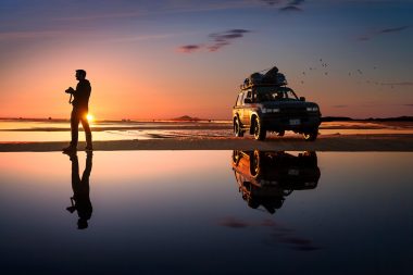 Photographer on Salar de uyuni salt flats during sunset