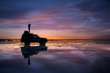 Automotive lifestyle photograph of photographer on car in sunse in Bolivia