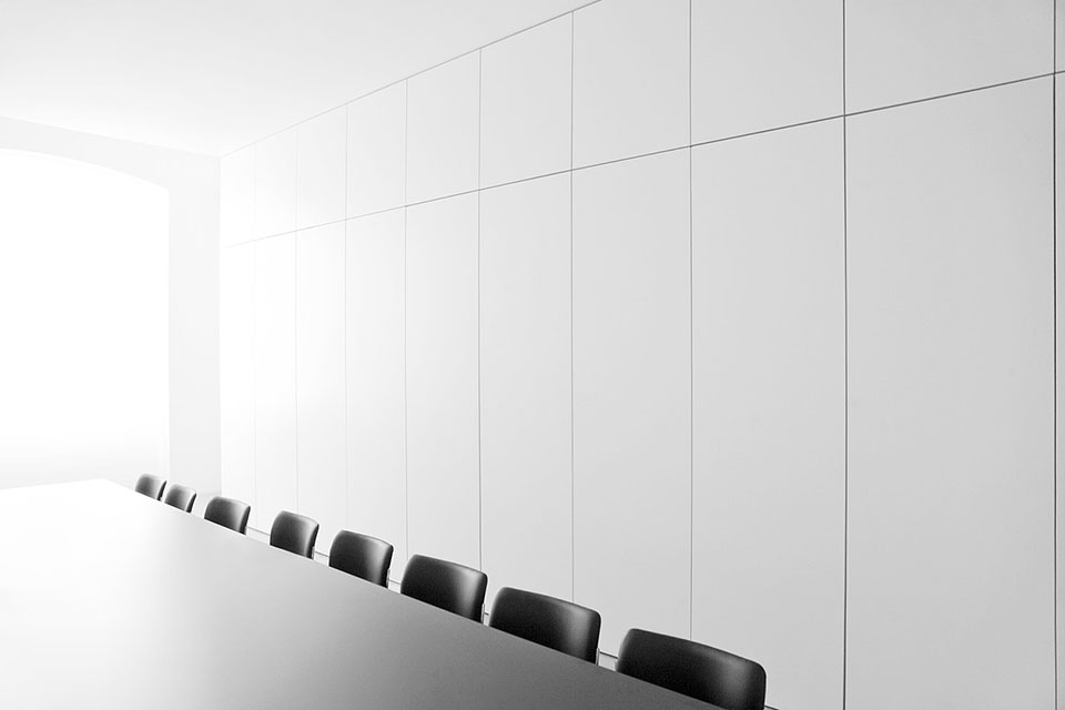 A corporate office interior with white walls and black chairs.