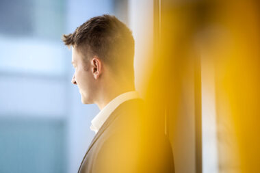 A man looking out of a window in a corporate office in London.
