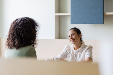 Two people talking over coffee in a corporate environment.