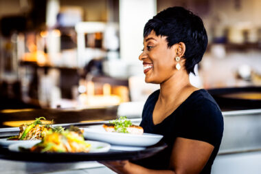 A woman carrying a tray of food at The OXO Tower Brasserie in London