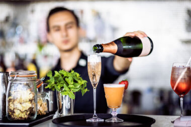 A man pouring a glass of champagne at a bar. Part of a Marketing photography project by Richard Boll.