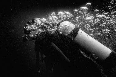A black and white photograph of a diver with bubbles.