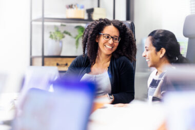 Two women laughing in a meeting in London.