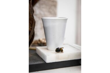 A sculpture of a polystyrene cup with a dead bee.