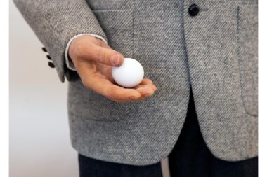 Close-up photograph of a figure holding an egg in the studio.