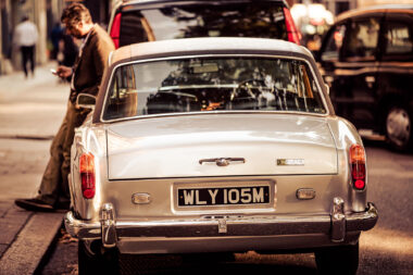 A man leaning against a Rolls Royce Corniche in London. Luxury brand photography from Richard Boll.