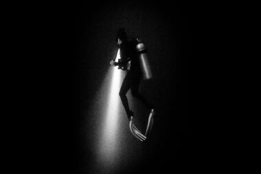 A diver at night with a torch in Egypt. Underwater photography by Richard Boll.