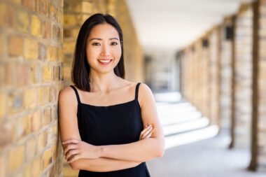 A corporate headshot of a woman leaning against a wall in London.