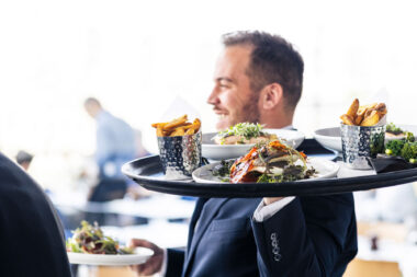 A hospitality photograph of a waiter carrying a large tray of food at the OXO Tower restaurant in London.