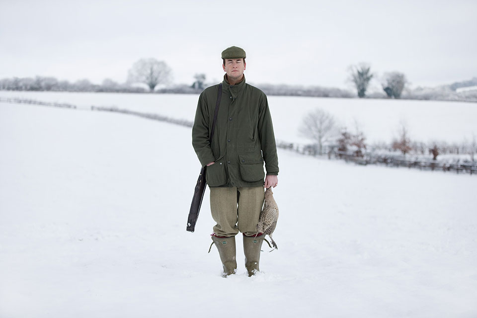A portrait of a man in a snow-covered field holding a pheasant from the project Death in the Afternoon. Richard Boll Photography, London.