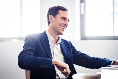 A man in a blue jacket in an office in London.