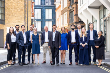 A corporate group photograph of thirteen people in a street in London.