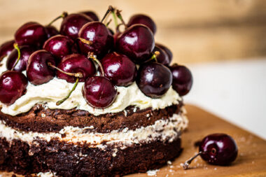 Red cherries on a chocolate cake photographed for Wildfire Design Studio for Holland Park School by Richard Boll.