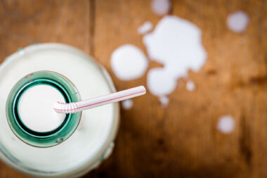 The top of a milk bottle with a straw and drops of milk. Nigel Slater Toast inspired image.