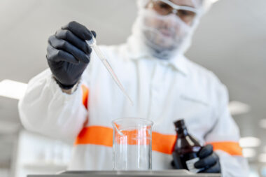 A corporate industrial photograph of a man holding a pipette over a beaker in a laboratory.