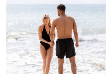 Two people holding hands by the sea.