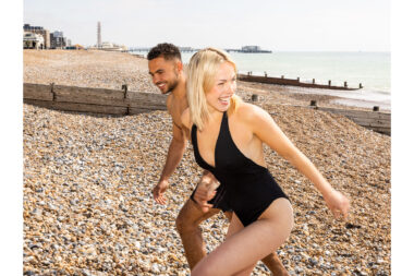 A laughing couple walking on a beach.