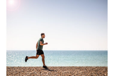 A man running on a beach photographed by London lifestyle photographer Richard Boll.