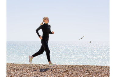 A woman running on a beach living an active lifestyle.