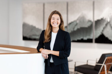 A corporate headshot of a woman in an office environment.