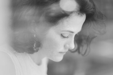 A black and white portrait of the artist Marie Harnett drawing in a cafe in London.