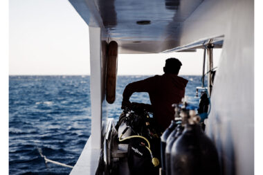 The silhouette of a man checking diving cylinders on a diving boat in the Red Sea in Egypt - documentary-styled lifestyle photography.