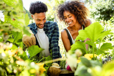 A man and a woman gardening together seen through green plants- intimate and authentic lifestyle photography by Richard Boll, London.