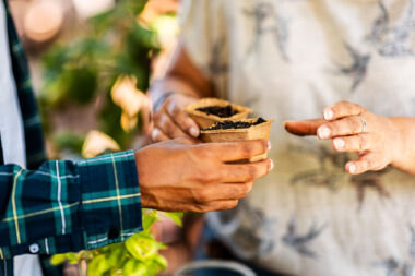 Close-up photography of hands passing small pots of soil and seeds between them during a lifestyle photography shoot.