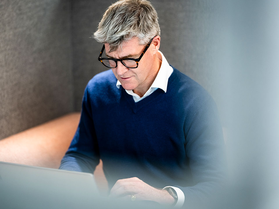 A man working at a laptop in a corporate office in London.
