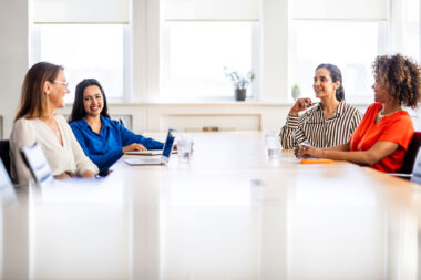 Four women having a meeting in a contemporary office space by lifestyle photographer Richard Boll.