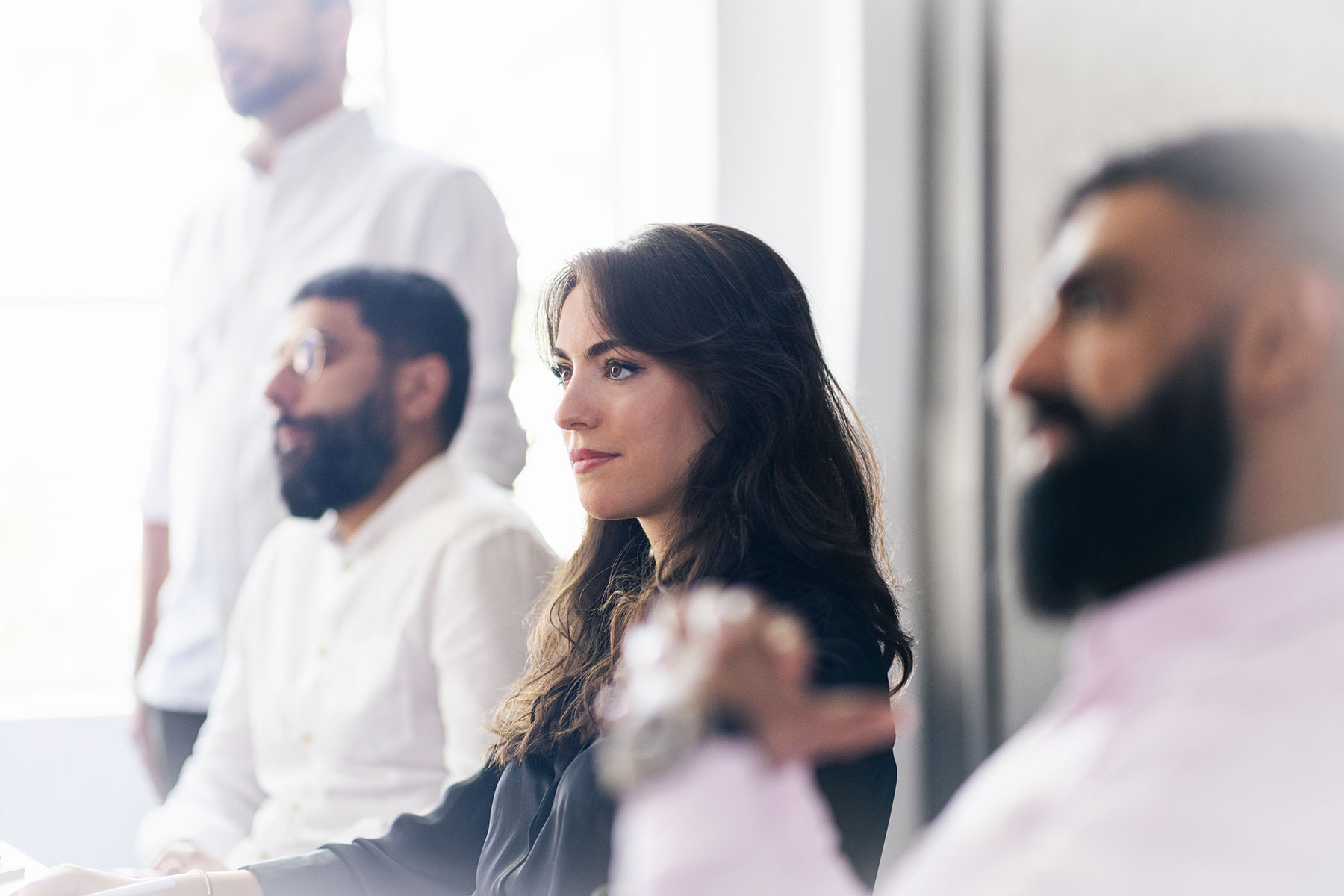 Candid photo of business professionals listening attentively during a corporate meeting, shot with natural window light by a London workshop photographer.